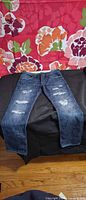 Front view of distressed dark blue slim jeans laid flat