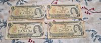 All four $1 Bank of Canada notes front view showing condition