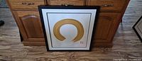 front view of framed artwork with gold circular brushstroke