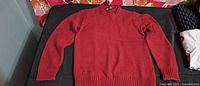 Front view of deep red Le Château crew neck knit sweater laid flat