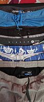 Stacked waistbands displaying O’Neill, U.S. Surf Club, Vissla labels and flamingo print