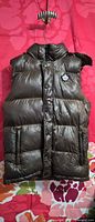 Front of olive-brown Toboggan Canada hooded puffer vest on hanger