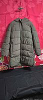 Front view of olive quilted puffer coat hanging