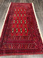 Full view of red Turkman wool rug on wood floor