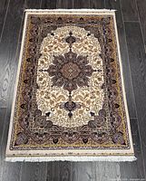 Full view of Kashan silk rug on dark wood floor