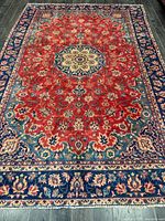 Full view of red-field Isfahan rug showing central medallion and navy floral border