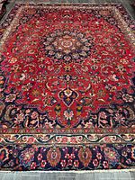 Full view of Mashhad wool rug showing red field, central medallion, navy border, fringe