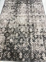 Full view of distressed charcoal, gray and ivory 5' x 7' area rug