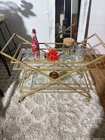 Front view of gold bar cart with glass shelves and included glassware