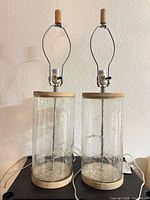 Front view of both lamps showing glass bodies, wood accents, harps and finials