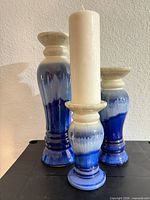 Three glazed ceramic candlesticks with pillar candle