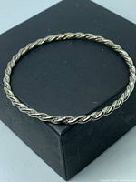 Top view of entire twisted rope silver bangle on box