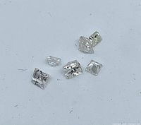 Six loose princess-cut diamonds on white background