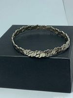 Front view of silver Cuban link bangle on box