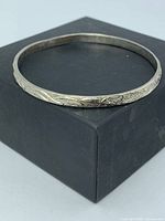 Top view of full circular etched silver bangle on black box