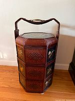 Full view of octagonal three-tier wicker basket showing lacquer panels and handle