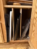 Vertical cabinet dividers showing cutting boards, black modular rack legs, metal baking sheets, wire cooling racks