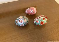 All three painted eggs displayed on wooden surface