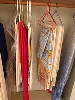 Group of tablecloths on hangers showing red, white, patterned pieces