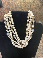 Front view of three-strand cream bead necklace on display bust