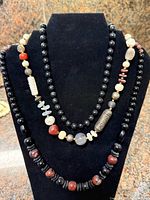 Front view showing three necklaces on display form