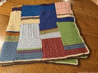 Folded crochet blanket showing varied color blocks and edging