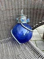 Front view of cobalt blue glass orb in metal spiral cage with hanging loop