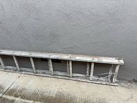 Full view of the ladder lying on concrete showing entire length and rungs