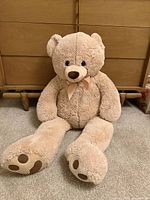 Front view of large beige teddy bear seated on carpet