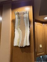 Full view of vertical ceramic wall sculpture mounted between wood panels