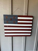 Front view of slatted wooden American flag with five metal stars hanging on wall