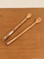 Two wooden hand back scratchers on tabletop, showing overall design