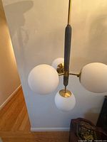 Full view of chandelier showing three glass globes and brass hardware