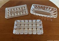 All three clear glass trinket trays on wooden surface