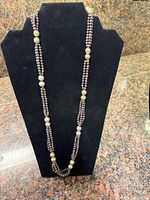 Full view of necklace hanging on display form showing bead arrangement and overall length