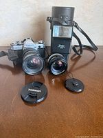 Front view showing Canon AE-1 body, Tamron lens, separate 50 mm lens, Vivitar 2000 flash, lens caps