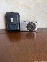 Front view of Canon PowerShot SD770 IS camera next to Canon leather case