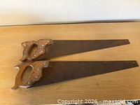 Two vintage carpenter hand saws on wooden surface