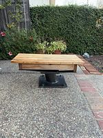 Angled front view showing entire coffee table, wood top, metal pedestal, base plate