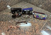 All seven pairs of glasses and three cases arranged on countertop