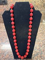 Full view of cinnabar bead necklace on display form