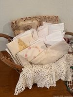 Basket filled with assorted linens showing crochet scarf and embroidered napkins