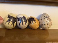 Front view of four decorative stone eggs lined up on shelf