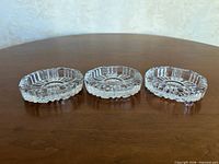 Three clear pressed glass dishes lined up showing side profile patterns