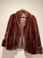 Full front view of brown fur jacket on hanger