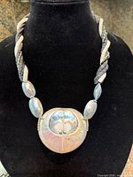 Full necklace on bust showing twisted heishi strands, oval beads and ammonite pendant