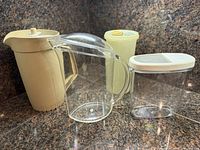 Front view of all four plastic pitchers and container grouped on countertop
