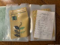 First open view showing fabric swatch with embroidered needle, spool and foliage plus handwritten notes