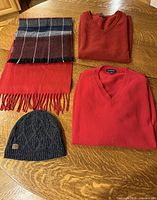 Overhead of two sweaters, two scarves, and beanie on table