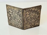 Hinged 800 silver double frame standing partially open, showing engraved floral design on both panels